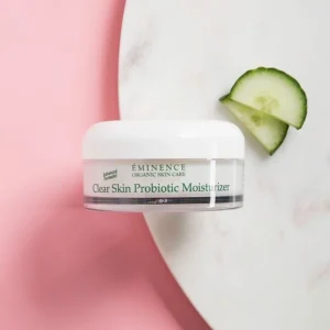 Clear+Ski+Moist – Damara Luxury Spa Vancouver Eminence Clear Skin Probiotic Moisturizer jar on a white marble surface with a pink background and a cucumber slice nearby.