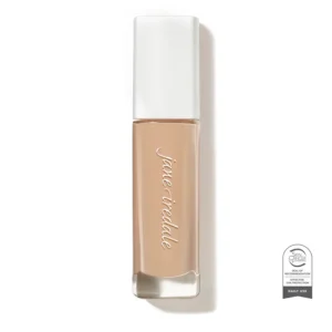Nude beige nail polish bottle with a white cap, brand name scripted vertically on the bottle, and a certification seal badge at bottom-right.