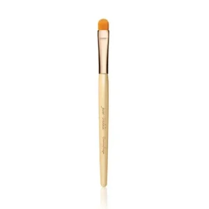 Concealer brush with a light wooden handle and orange bristle tip.