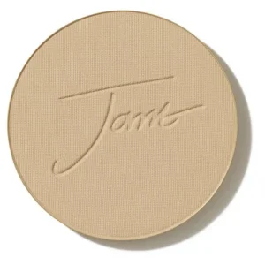 Round beige pressed powder compact with embossed cursive signature motif on lid.