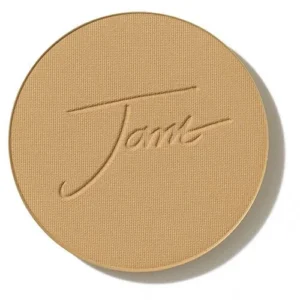 Round pressed powder compact in light beige with an embossed cursive signature on the lid, viewed from above.
